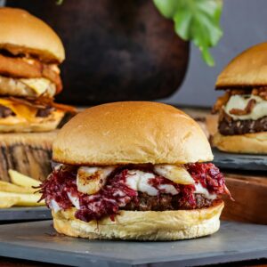 Mouthwatering capture of three gourmet burgers with diverse toppings and a side of fries.