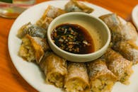 Tasty Asian spring rolls served with a savory dipping sauce on a white plate.