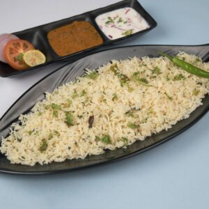 Freshly prepared jeera rice served with chutney, yogurt, and salad.